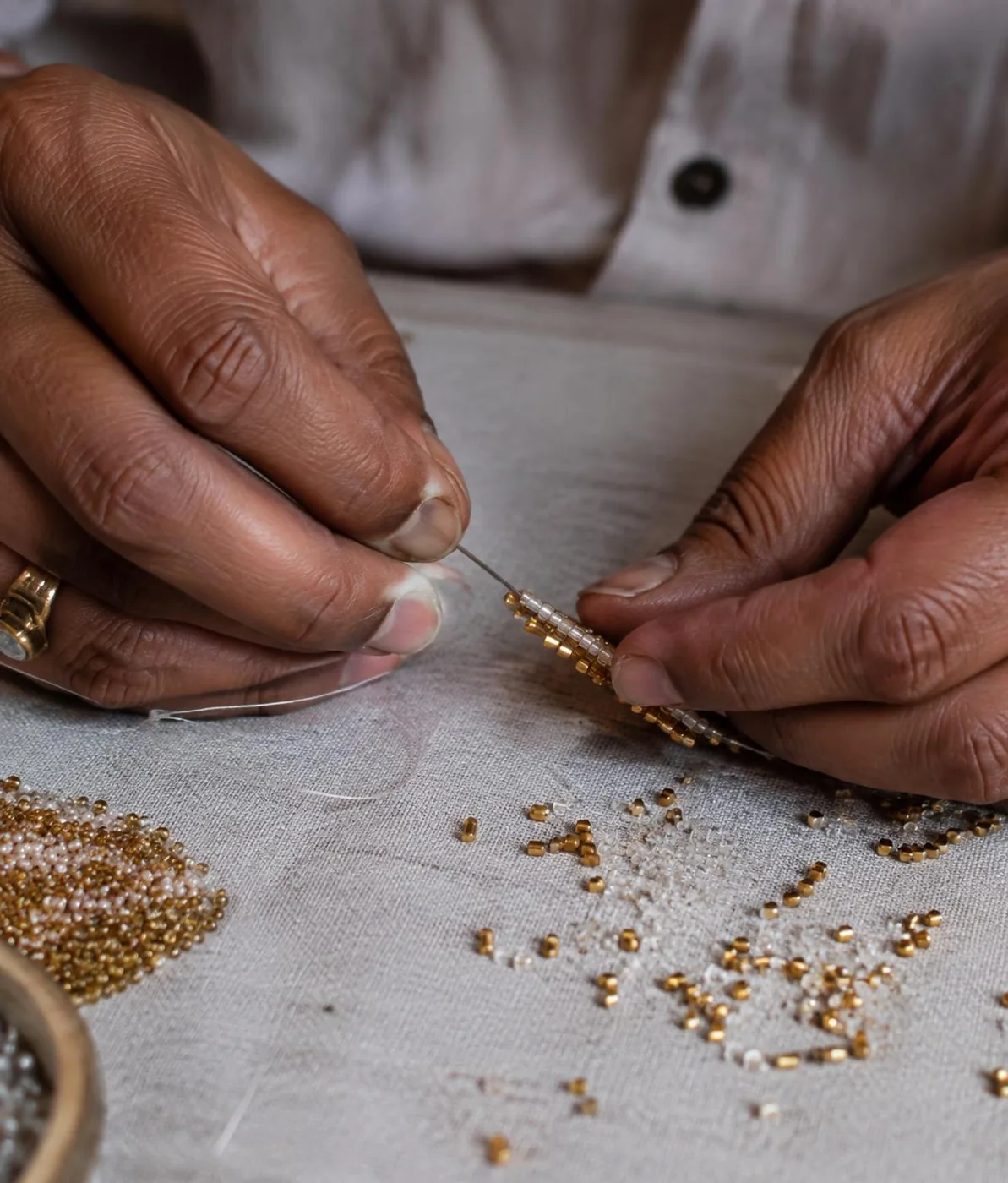 Hands threading beads, an illustration of jewellery-making technique